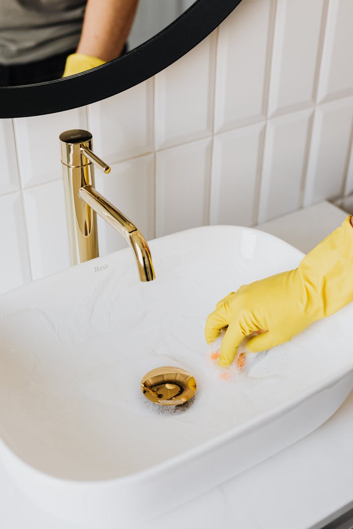 Faceless man cleaning sink in bathroom